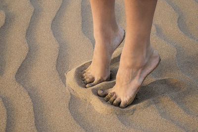 Detail of female legs on golden sea sand of the beach close up.