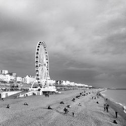 Carousel in amusement park against cloudy sky