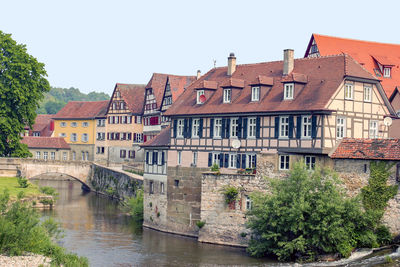 Arch bridge over river amidst buildings against clear sky