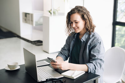 Young woman embracing the modern work environment. using laptop computer and mobile phone at office