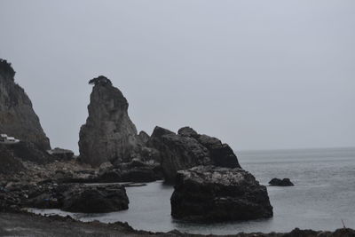 Rock formation on beach against sky
