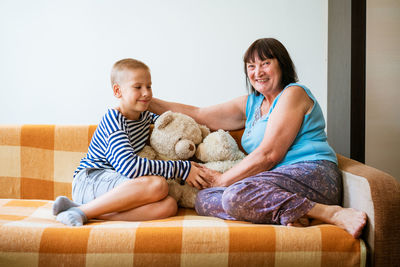 Mother and daughter sitting on sofa at home