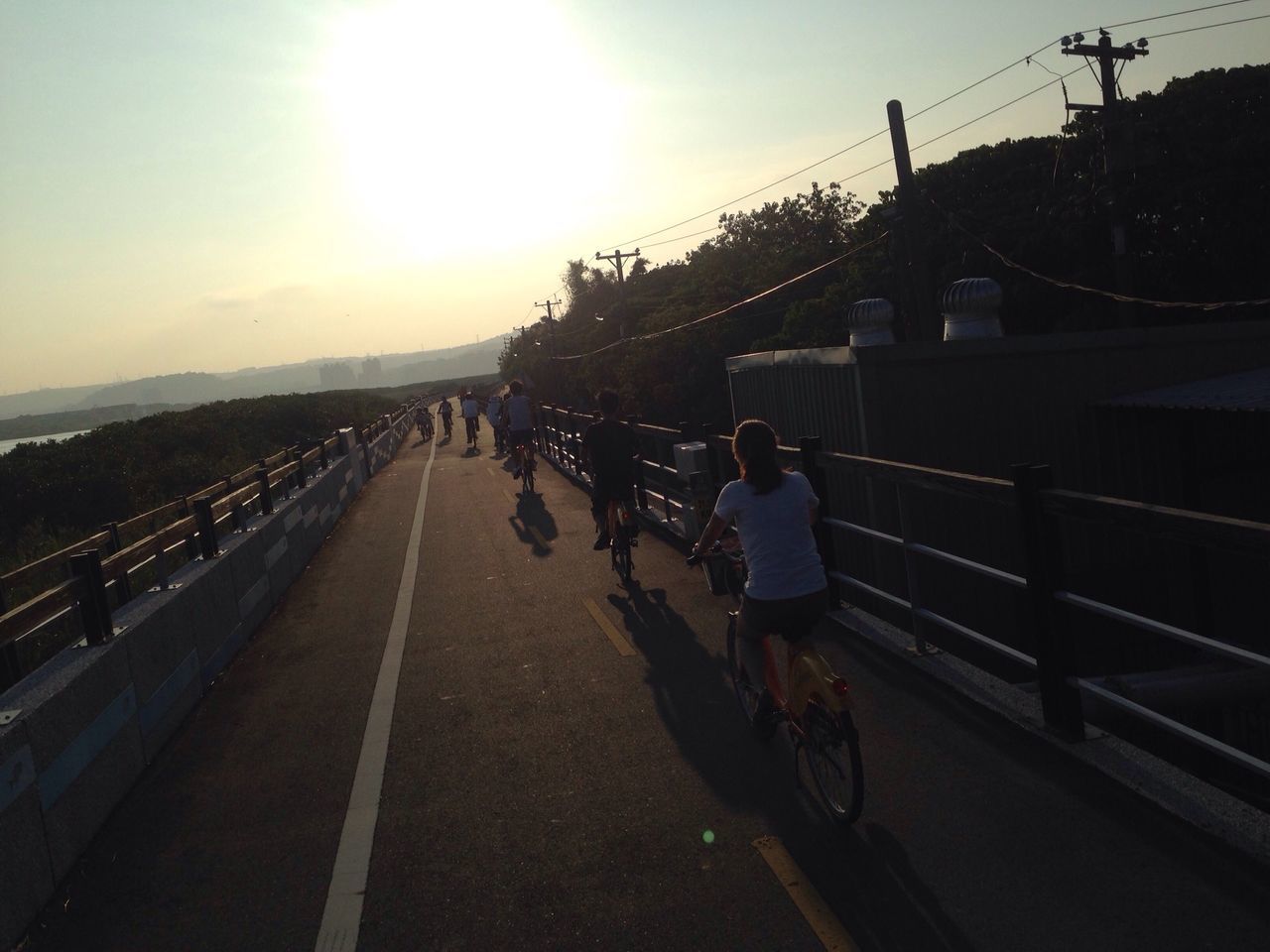 sunset, the way forward, transportation, sky, men, walking, lifestyles, leisure activity, person, diminishing perspective, built structure, railing, vanishing point, rear view, architecture, road, connection, sunlight, silhouette