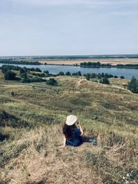 Rear view of woman sitting on field against clear sky