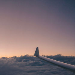 Airplane wing against sky during sunset