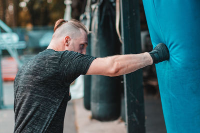 Side view of young man practicing boxing while standing outdoors