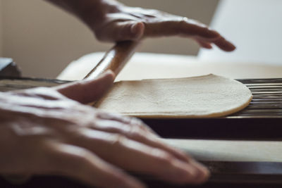 Close-up of old metal strings spaghetti machine with hands on rolling pin