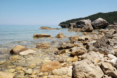 Rocks by sea against clear sky