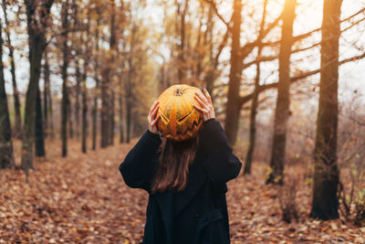 Woman holding jack o lantern in forest