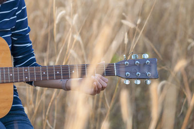 Midsection of woman playing guitar amidst plants