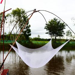 Close-up of clothes hanging on tree by lake against sky