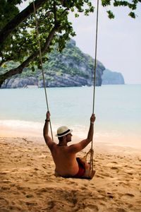 Man on swing at beach