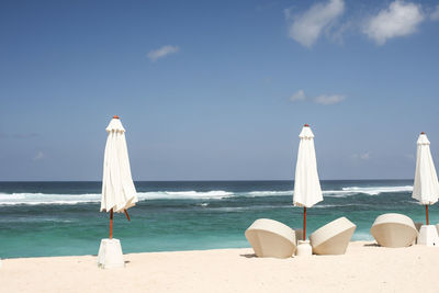 Lounge chairs on beach by sea against sky