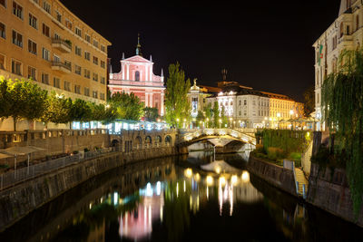 Bridge over canal amidst buildings in city at night