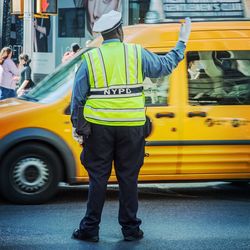 Rear view of traffic cop controlling traffic on street