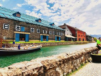 Buildings by canal against sky in city