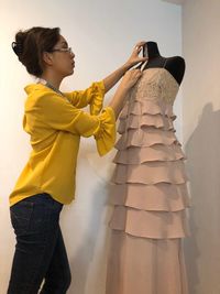 Side view of woman standing against yellow wall