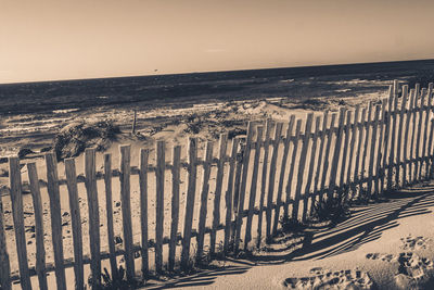 Wooden posts on beach against sky