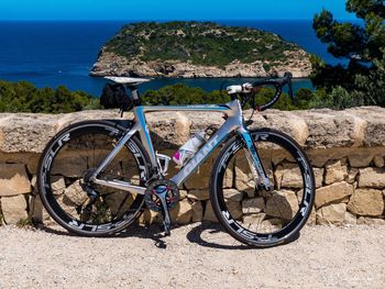 Bicycles on rock by sea against sky