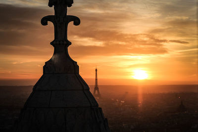 High section of religious building with eiffel tower in background during sunset