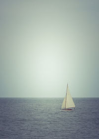 Sailboat sailing on sea against clear sky