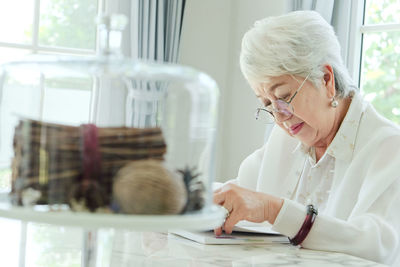 Senior woman reading book while sitting at home