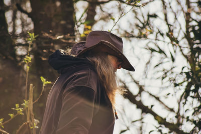 Midsection of woman standing by tree in forest