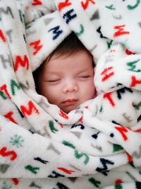 Close-up of cute baby girl sleeping while wrapped in blanket