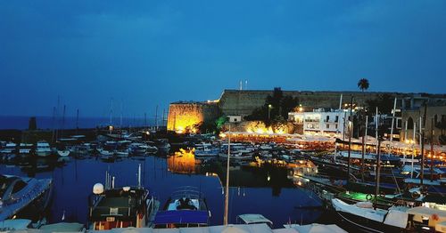 Boats moored at harbor against sky at night