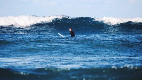 Man surfing in sea against sky