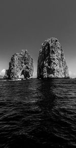 Rock formation in sea against clear sky