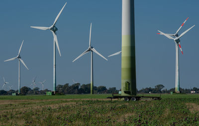 Windmills on field against clear sky