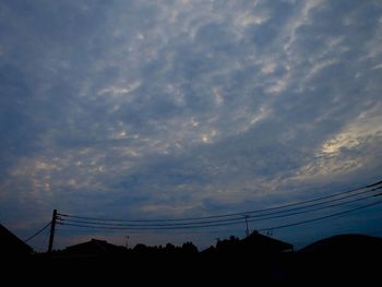 Low angle view of silhouette electricity pylon against sky