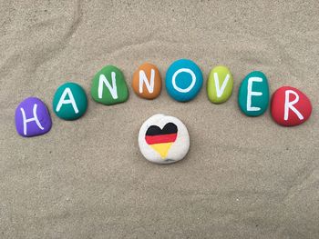 High angle view of hannover text with heart shape german flag stones at beach