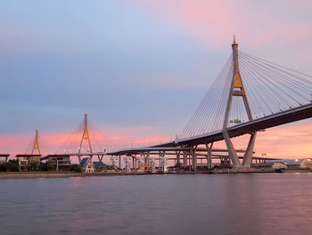 Suspension bridge over river against sky during sunset