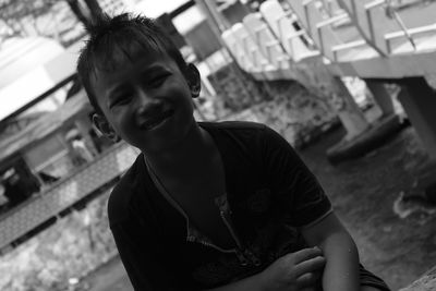 Portrait of boy sitting by bridge