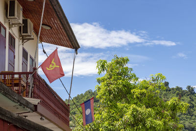 Low angle view of flag amidst trees and buildings against sky