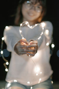 Close-up of young woman holding illuminated lamp