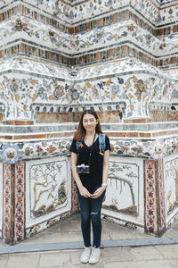 Portrait of woman standing against building