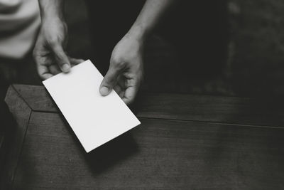 Close-up of hand holding paper on table