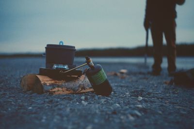 Close-up of food being cooked at campsite with man standing in background during dusk