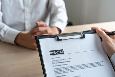 Close-up of hand holding paper on table