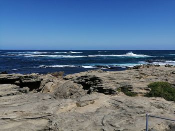 Scenic view of beach against clear blue sky