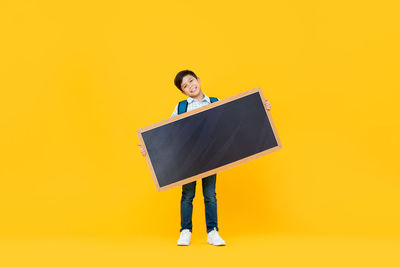 Portrait of smiling man standing against yellow background