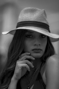 Close-up portrait of young woman holding hat
