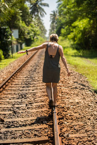 Rear view of man walking on railroad track