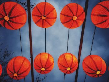 Low angle view of illuminated lanterns hanging against cloudy sky