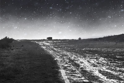 Dirt road on field against sky at night