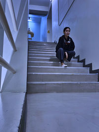 An asian office worker sitting on fire exit stairway with her face mask hanging on the neck