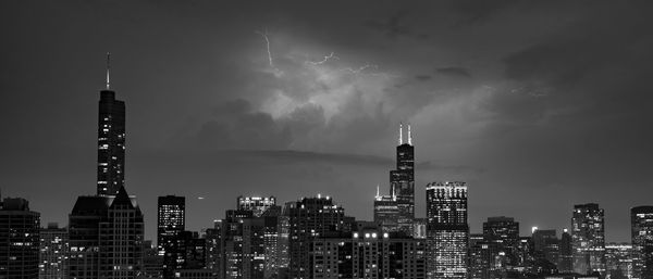 Illuminated buildings in city against sky at night